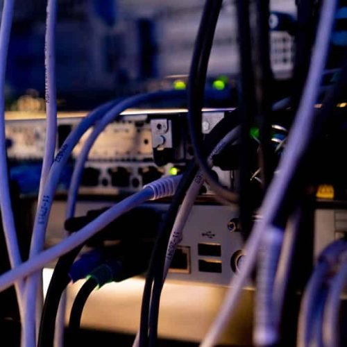 a bunch of patch network cables sorted in a rack cabinet leading from a patch panel in a server rack in data center room internet cloud storage