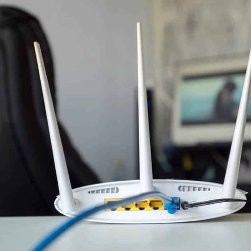 Close up of a wireless router on table at home with desktop computer background